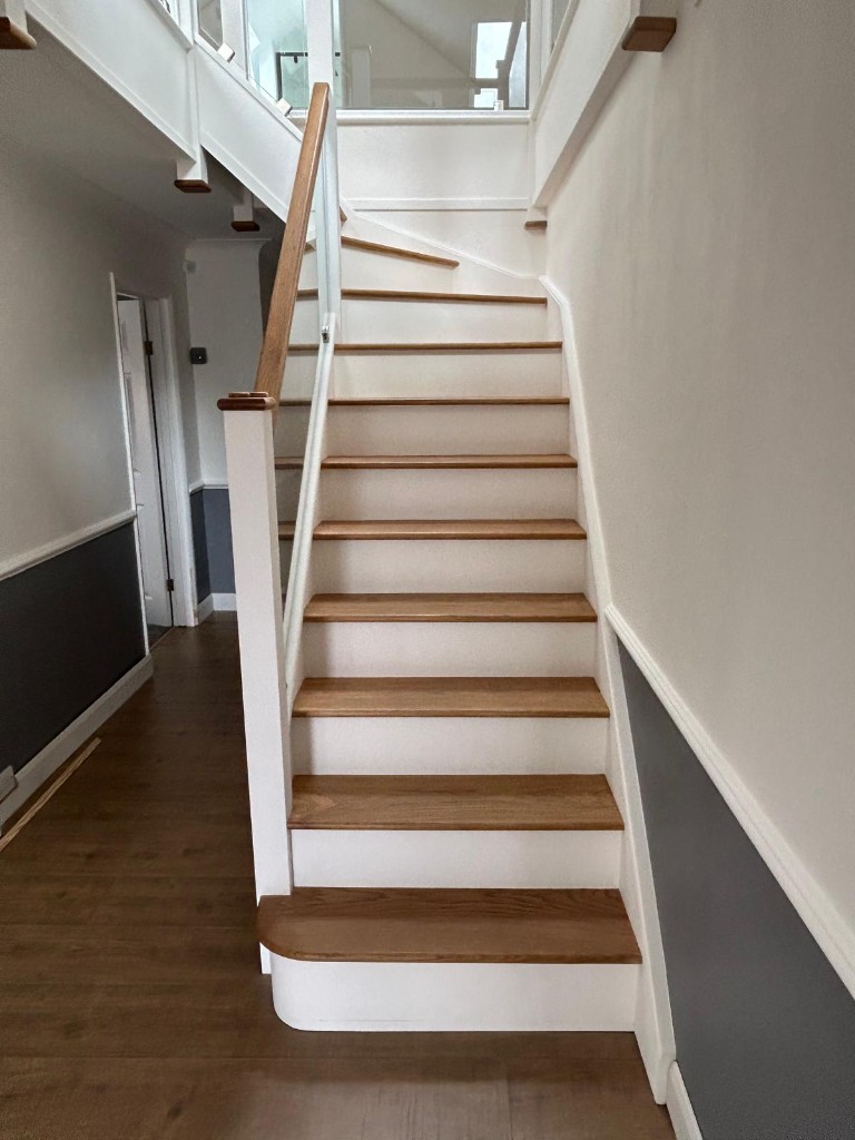 Bottom of a custom oak and pine staircase with oak newel and glass balustrading in Cuxton, Kent