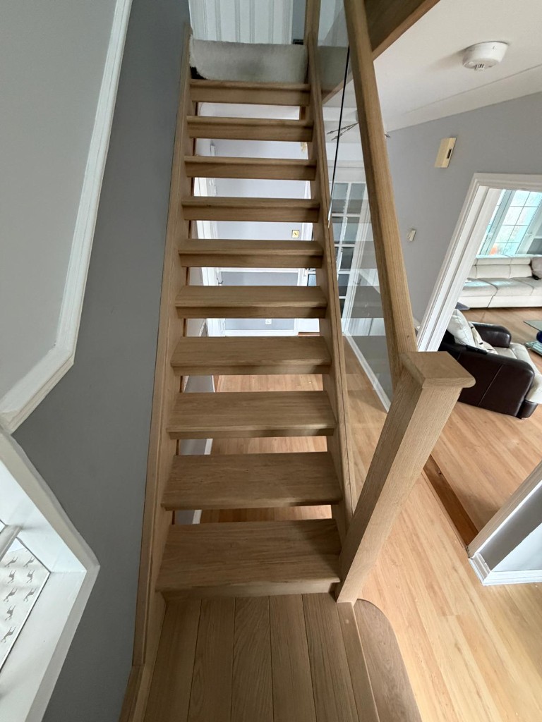 Looking down a custom solid oak staircase with glass balustrading in Strood, Kent