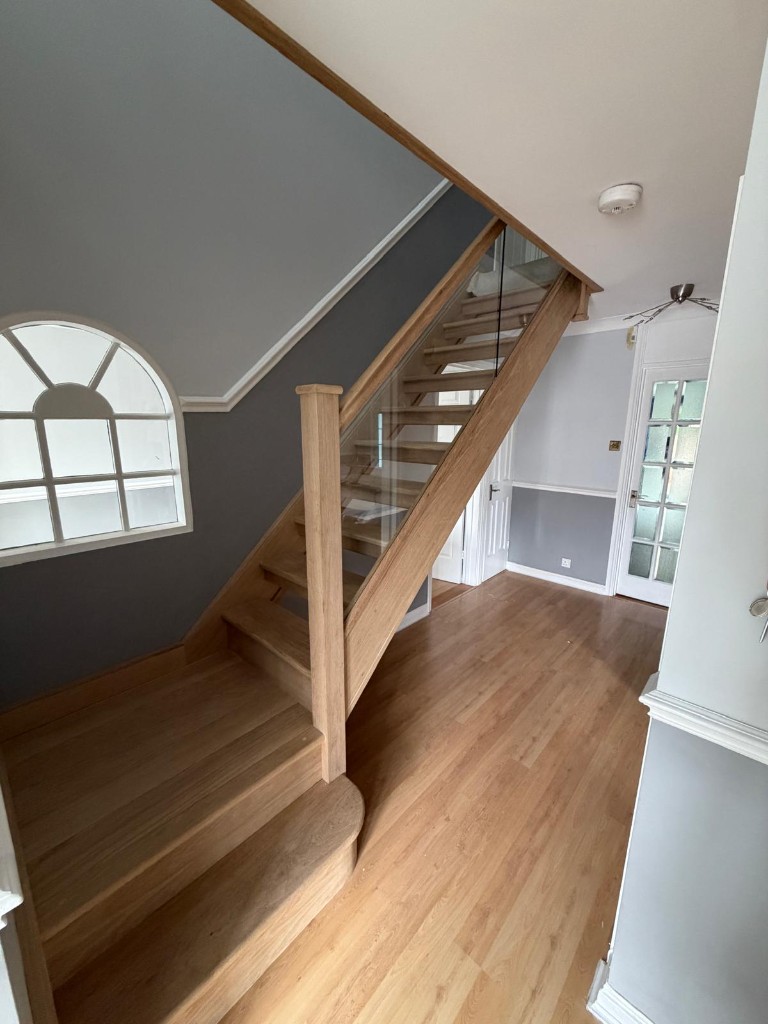 Landing view of a custom solid oak open plan staircase with glass balustrading in Strood, Kent