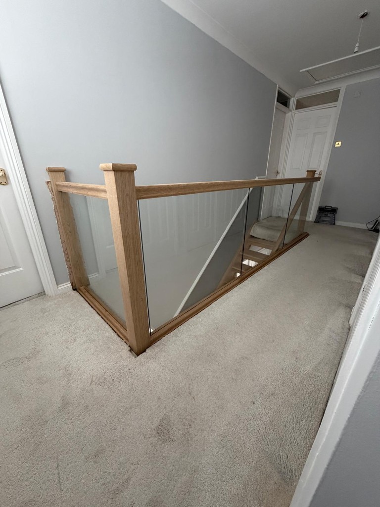 Upper landing glass balustrade on a custom solid oak staircase project in Strood, Kent